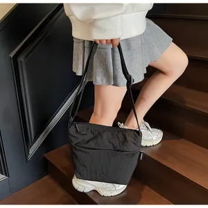 Dettaglio della borsa a tracolla in nylon plissettato nero indossata dal modello