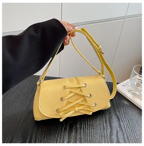Detail view of the yellow pleated leather texture and crossbody strap with metal eyelets