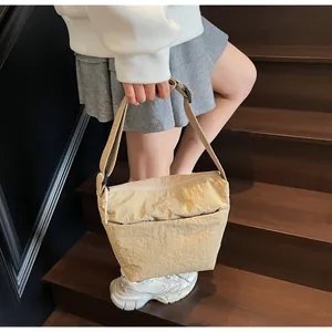 Dettaglio della borsa a tracolla in nylon beige con tracolla regolabile indossata dal modello