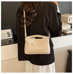 Detail der beigen Beuteltasche mit Spitzenschleife, Perlen und handgewebtem Griff am Modell