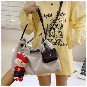 Detail of beige canvas tote bag featuring brown woven straps and cute plush pendant