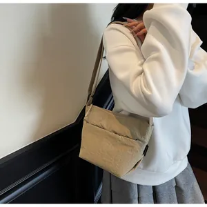 Dettaglio macro della borsa a tracolla in nylon beige con etichetta tessuta laterale
