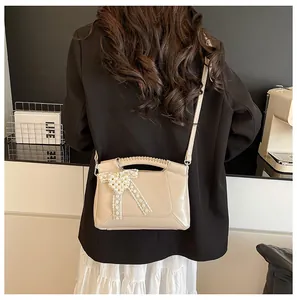 Detail der cremefarbenen Beuteltasche mit Spitzenperle und geflochtenem Griff