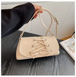 Detail view of cream-colored pleated crossbody bag with ribbon lace-up decoration