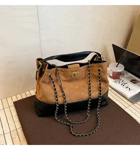 Detailed view of bicolor quilted tote bag with golden lock on a leather and suede finish