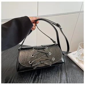 Detail of black bow shoulder bag featuring corset-style lacing and silver eyelets