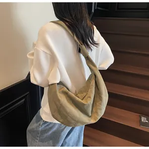 Back view of model wearing a large olive green crossbody dumpling bag with quilted stitching