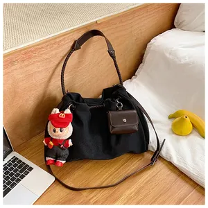 Detailed view of black textured tote bag with brown woven strap and mini pouch