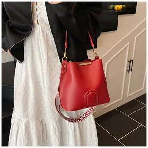 Detail of red leather bucket bag featuring a woven strap and gold metal hardware hooks