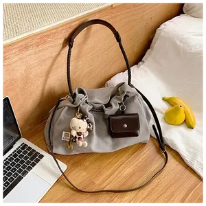 Detailed view of grey canvas tote bag with woven handles and cute character keychain