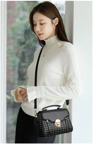 Close-up of vintage patchwork plaid crossbody bag with gold rotating lock on white sweater
