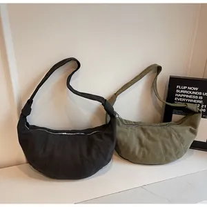 Detail of minimalist crescent shoulder bags in black and olive green with quilted seams