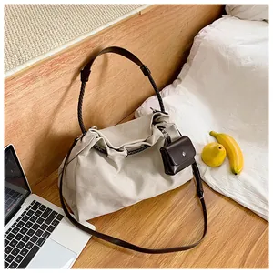 Detail of off-white canvas tote bag with brown woven handles and mini leather accessory