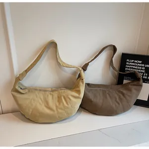 Detail view of large minimalist crescent bags in beige and coffee suede with curved seams