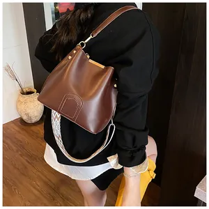 Detail of brown leather bucket bag with wide geometric strap and metallic rivets