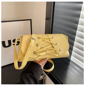 Detailed view of yellow pleated leather bag with lace-up design and adjustable strap