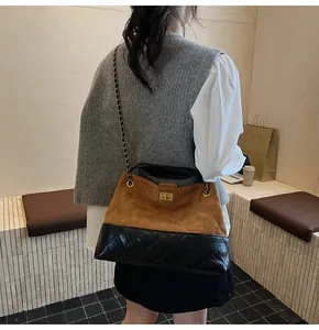 Detail of the chain strap and quilted two-tone tote bag on a model in a warm setting