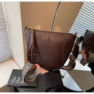 Detail der dunkelbraunen Lederbeuteltasche mit Fransequaste und breitem Ethno-Gurt