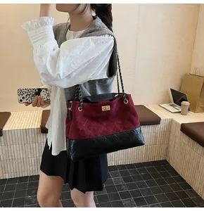 Detail of burgundy and black quilted tote bag with gold chain strap on shoulder