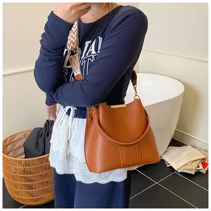 Detail of brown leather bucket bag with jacquard pattern strap and gold metal hardware