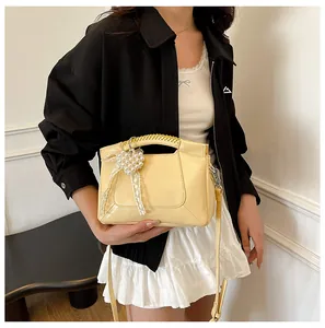 Detail der gelben Beuteltasche mit Flechtgriff und elegantem Perlen-Spitzen-Bogenanhänger