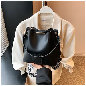 Detail of black matte leather bucket bag featuring gold hardware and a geometric strap