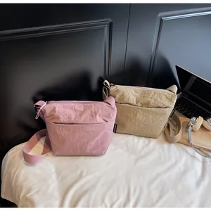 Dettaglio di borse a tracolla in nylon rosa e beige con cinturini in tessuto e logo