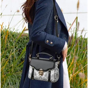 Sac bandoulière vintage aux motifs orientaux et boucle dorée porté avec un manteau en laine