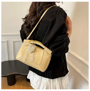 Chic Cremefarbene Beuteltasche mit Spitzenschleife und geflochtenem Griff an einem Modell