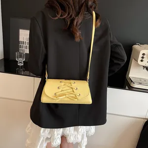 Chic pale yellow bow crossbody bag shown from behind on a stylish black blazer