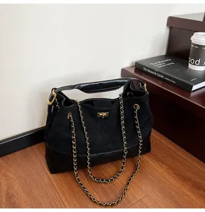 Close-up of quilted suede and leather tote with gold twist lock and chain strap