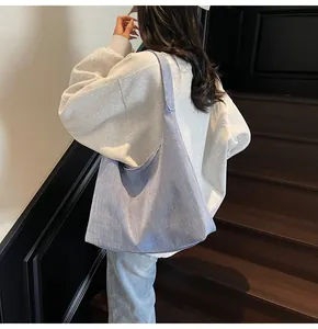 Detailaufnahme des Denim-Stoffs und des nahtlosen Schultergurts der großen Tragetasche