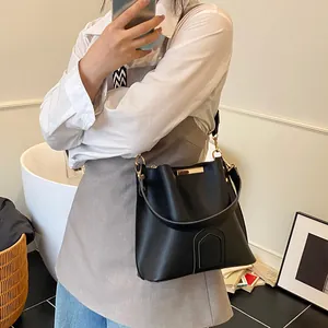 Classic black leather bucket bag with gold hardware and wide strap shown in a modern interior