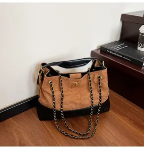Detail of the chain strap and gold twist lock on this two-tone quilted leather tote bag