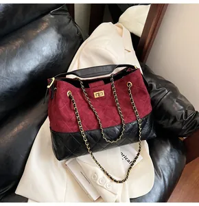 Detailed close-up of burgundy suede and black leather patchwork bag with gold metal lock