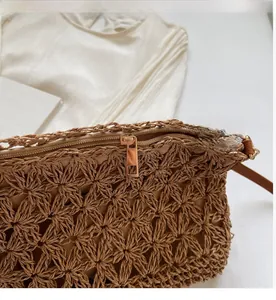 Macro detail of high-quality gold metal zipper and woven texture on brown straw tote bag