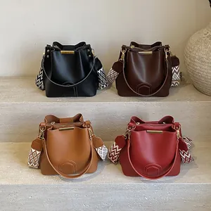 Minimalist bucket bag in four colors with geometric jacquard strap on stone steps