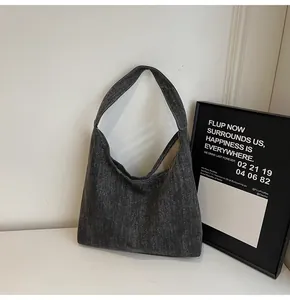 Detail einer großen dunkelgrauen gewaschenen Denim-Tasche auf weißer Fläche