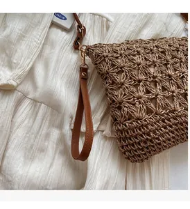 Close-up of woven straw tote bag with brown leather handles and gold metal hooks
