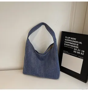 Detailansicht der lässigen blauen Denim-Hobo-Tasche mit breitem Trageriemen und weichem Stoff