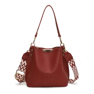 Burgundy matte leather bucket bag with golden hardware and geometric woven strap