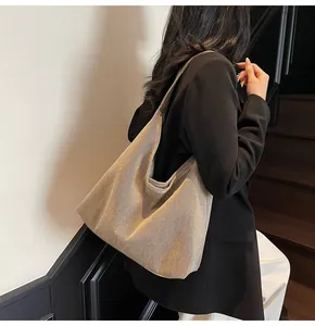 Detailansicht einer großen Metallic-Canvas-Tragetasche, die stilvoll über der Schulter getragen wird