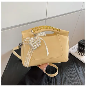 Detail der beigen Beuteltasche mit geflochtenem Griff und Perlen-Herz-Anhänger-Zubehör