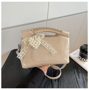 Detail der beigen Beuteltasche mit Perlenherz-Anhänger, Spitzenschleife und Webgriff