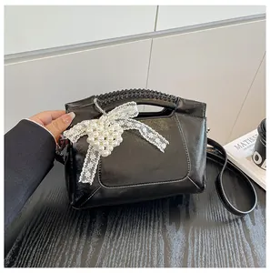 Details der schwarzen Beuteltasche mit Spitzenschleife, Perlenherz und Webgriff