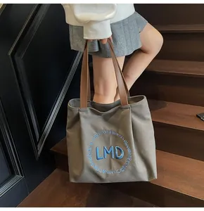Detail of dark gray canvas tote bag with brown leather handles and LMD blue print