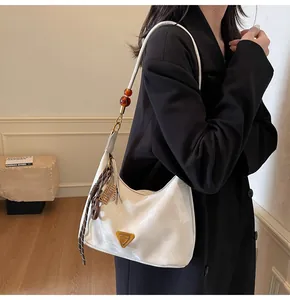 Dettaglio borsa hobo bianca lucida con placca triangolare dorata e ciondoli di perle