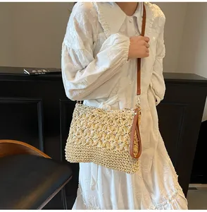 Detail of hollow-out floral weave texture on straw tote bag with brown leather straps