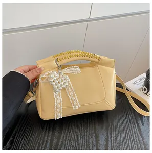Detail der beige Handtasche aus Leder mit geflochtenem Griff und Spitzen-Herz-Anhänger