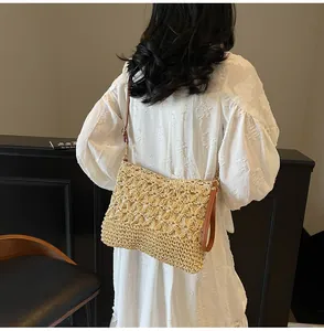 Detail of star-shaped hollow woven straw tote bag with brown leather strap on model